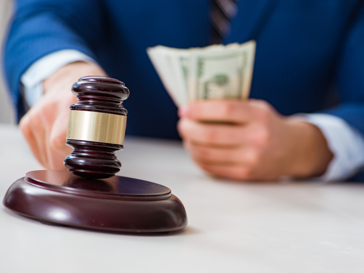 A man in a suit hitting a gavel and a handful of money.